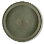 A large Chinese grey stoneware celadon dish, Ming dynasty, 16th/17th century, the raised central