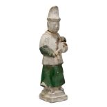 A Chinese pottery figure of an attendant, Ming dynasty, 16th century, modelled standing holding a