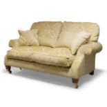 A cream upholstered three piece suite, comprising two seater settee and two matching armchairs, each