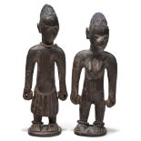 A pair of Yoruba male and female 'Ibeji' figures, 20th century, each modelled as standing figures,