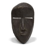 A Dan mask, Ivory Coast, 20th century, of oval form with carved faceted surfaces and stylised