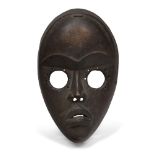 A Dan mask, Ivory Coast, 20th century, of oval form with circular eyes and stylised features, 22cm