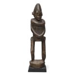 A Dogon figure, Mali, 20th century, of stylised form, carved as a standing figure on circular