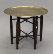 An Eastern brass topped folding table. 57 cm diameter.