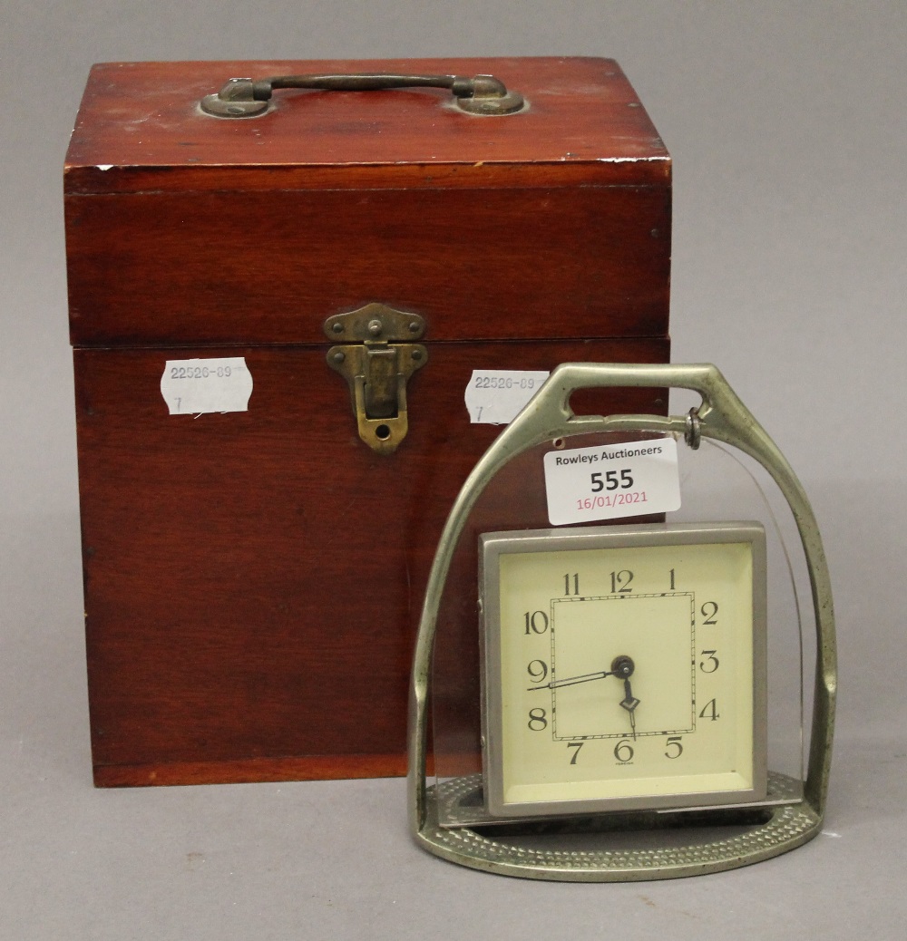 A stirrup form clock in a wooden box. The clock 14 cm high.