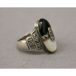 A mother-of-pearl, black jet and marcasite ring. Ring size L.
