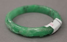 A carved apple green jade bangle. 7.5 cm diameter.