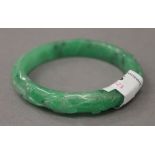 A carved apple green jade bangle. 7.5 cm diameter.