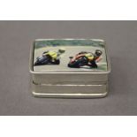 A silver pill box depicting motorbikes. 3 cm wide.