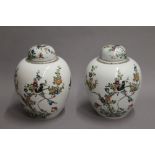 A painted pair of 19th century famille verte porcelain ovoid vases and covers. 27 cm high.
