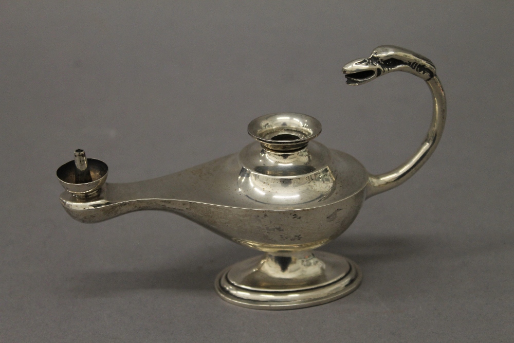 A silver table lighter formed as an oil lamp. 14 cm long. 106.8 grammes total weight.