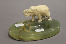 An early 20th century onyx ashtray mounted with an ivory elephant. 15 cm wide.