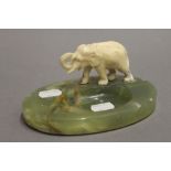 An early 20th century onyx ashtray mounted with an ivory elephant. 15 cm wide.