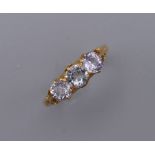 An unmarked, probably 18 ct gold, three stone possibly white sapphire ring. Ring Size N/O. 3.