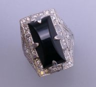 An Art Deco onyx and diamond white gold cocktail ring. Ring size N/O. 13.