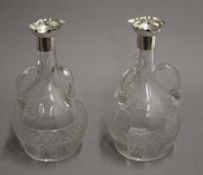 A pair of Edwardian glass and silver table carafes with three handles to the body,