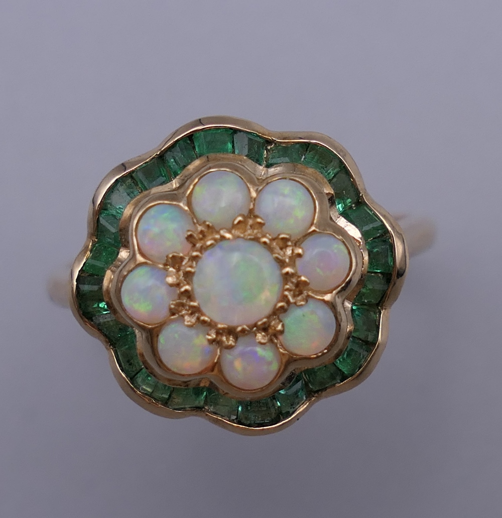 A 9 ct gold, opal and emerald ring. Ring size L/M. 2.6 grammes total weight.