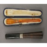 A cased cheroot holder and another. The former 9 cm long.