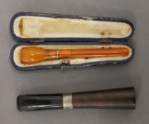 A cased cheroot holder and another. The former 9 cm long.