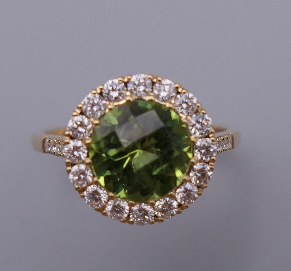 An 18 ct gold, peridot and diamond ring with diamond shoulders. Ring Size M. 3.
