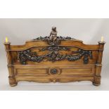 A Victorian ornately carved rosewood tester bed decorated with cherubs, putto and floral swags.