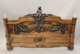 A Victorian ornately carved rosewood tester bed decorated with cherubs, putto and floral swags.