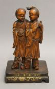 A pair of late 19th century Chinese carved wooden figures, mounted on a wooden plinth. 26 cm high.