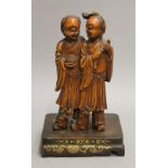 A pair of late 19th century Chinese carved wooden figures, mounted on a wooden plinth. 26 cm high.