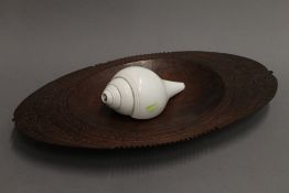 A South Sea carved wooden food dish and an engraved conch shell horn. The bowl 48 cm wide.