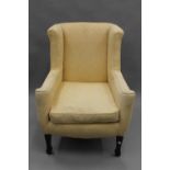 An Edwardian yellow upholstered wing back armchair. 73 cm wide.