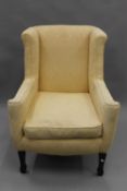 An Edwardian yellow upholstered wing back armchair. 73 cm wide.