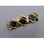 An 18 ct gold ring set with three sapphires and two small diamonds. Ring size W.