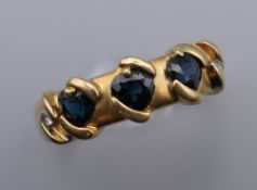 An 18 ct gold ring set with three sapphires and two small diamonds. Ring size W.