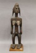 A Bamana carved wooden tribal figure, mounted on a later plinth. 76 cm high.