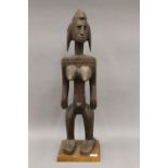 A Bamana carved wooden tribal figure, mounted on a later plinth. 76 cm high.