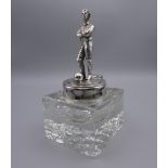 A silver plate mounted glass inkwell, the lid surmounted with a footballer. 17 cm high.