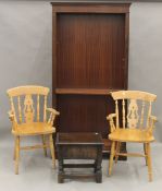 A modern bookcase, a white painted cupboard, a box stool and a pair of modern chairs.