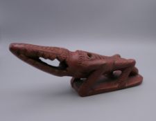 An Egyptian red ware bath rasp, formed as a crocodile. 20 cm long.