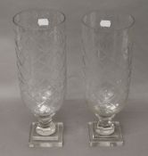 A pair of glass hurricane lamps. 34 cm high.