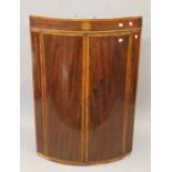 A George III mahogany inlaid bow front corner cupboard. 111 cm high.