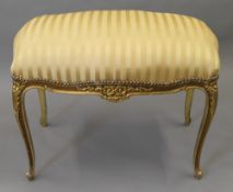 An upholstered gilt stool. 90 cm wide.