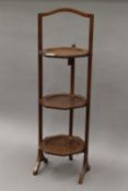 An Edwardian mahogany three-tier folding cake stand. 82 cm high.