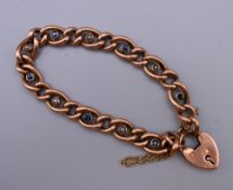 A 9 ct gold seed pearl and sapphire set bracelet with a 9 ct gold padlock. 19 cm long. 12.