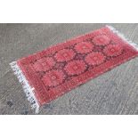 A red ground rug. 212 x 98 cm.