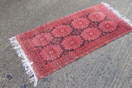 A red ground rug. 212 x 98 cm.
