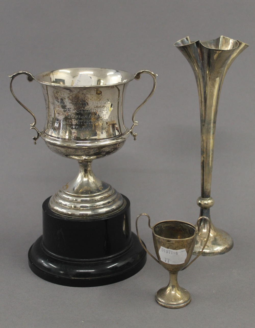 A silver bud vase, a small silver trophy cup and a broken silver trophy cup. The former 22 cm high.