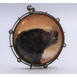 A framed painted mother-of-pearl pendant decorated with a dog. 3.5 cm diameter.
