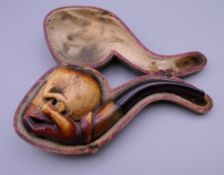 A cased Victorian Meerschaum pipe formed as a skull and hand. 13 cm long.