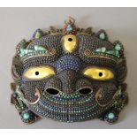 A Tibetan copper cabochon mounted mask. 24.