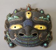 A Tibetan copper cabochon mounted mask. 24.